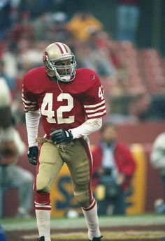 a football player standing on the field with his hands in his pockets and wearing a helmet