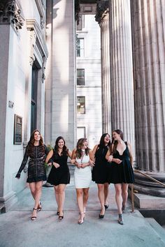 four women are walking down the steps in front of an old building with columns on either side