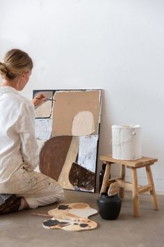 a woman sitting on the floor in front of a painting