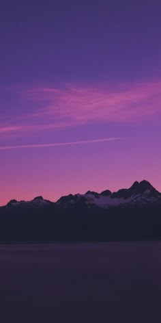 the sky is purple and pink with mountains in the background