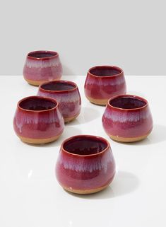 six red bowls sitting on top of a white table next to each other in a circle