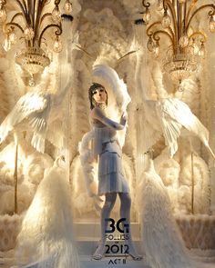 a mannequin dressed in white with feathers and chandeliers