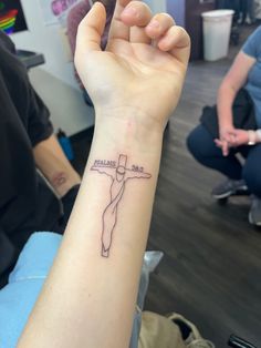 a person with a tattoo on their arm holding up a cross and the words jesus christ