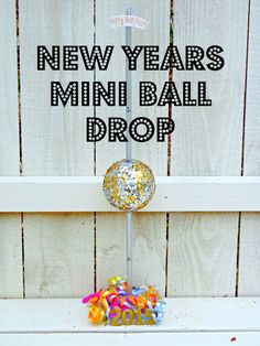 a new year's mini ball drop on top of a white shelf next to a wooden fence