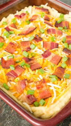 an uncooked pizza with bacon and cheese in a red casserole dish