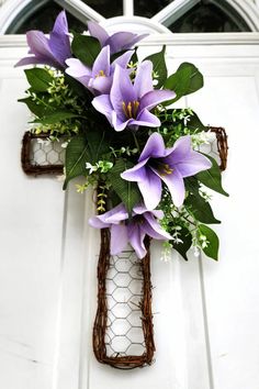 a cross decorated with purple flowers hangs on the front door's white painted door