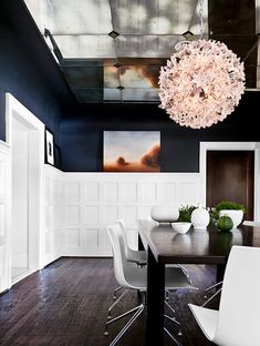 a dining room table with white chairs and a chandelier hanging from the ceiling