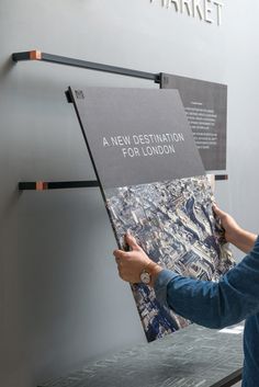 a person holding up a map in front of a sign that says a new destination for london