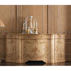 an ornately decorated sideboard with gold paint and decorative carvings on the sides, along with a lamp