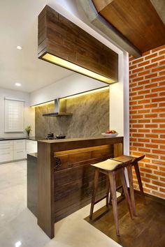 a kitchen with an island and stools next to it in front of a brick wall