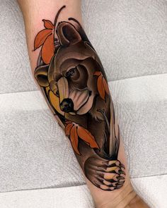 a bear with leaves on his leg is shown in this tattoo design by the artist