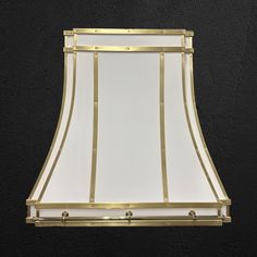 a gold and white lamp shade hanging from the ceiling in front of a black wall