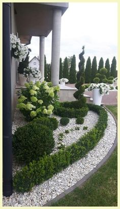 a garden with white and green flowers in the center, surrounded by graveled walkway