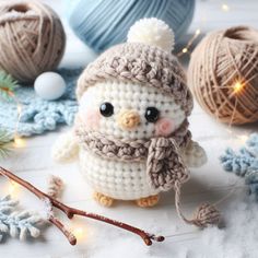 a small crocheted owl with a hat and scarf sitting next to balls of yarn