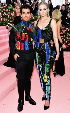 two people standing next to each other on a pink carpet