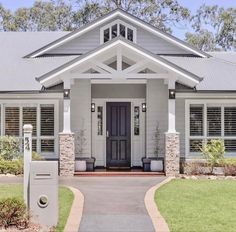 a gray house with white trim and black shutters on the front door is shown