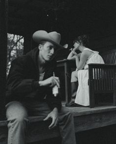 a man sitting on a bench next to a woman with a cowboy hat over her head