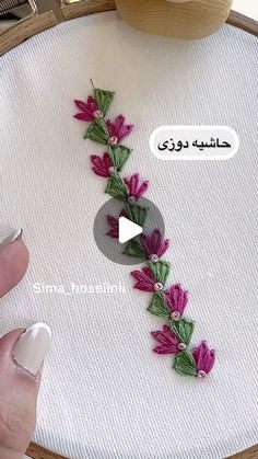 a person is stitching flowers on a piece of fabric with their thumbnails