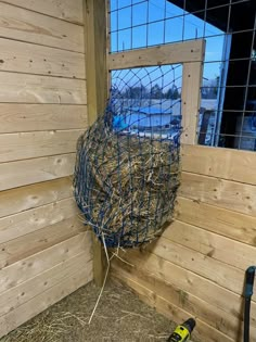 a cage with hay inside of it next to a fenced in area and tools on the ground