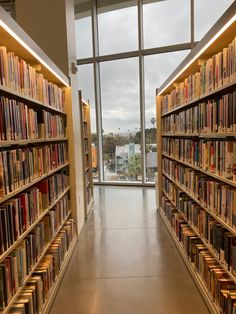 a long row of bookshelves filled with lots of books in front of a large window