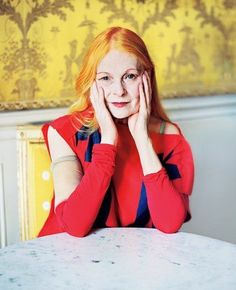 a woman sitting at a table with her hands on her face and looking into the camera