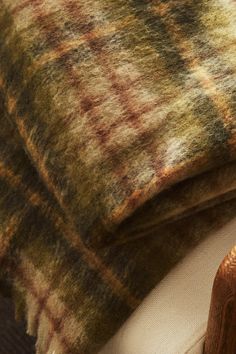 a close up of a blanket on top of a chair with a wooden arm rest