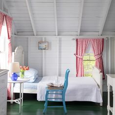 a bedroom with white walls and red curtains on the windowsills is decorated in blue and pink