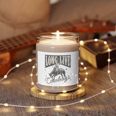 a candle sitting on top of a table next to a string of lights and a guitar