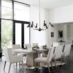 a dining room table with white chairs and a chandelier hanging from the ceiling