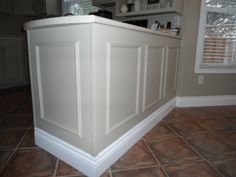 the corner of a kitchen with tile flooring and white cabinetry on the wall