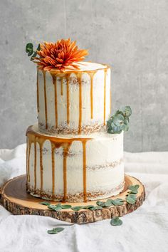 a three tiered cake with caramel drizzle and an orange flower on top