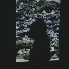 a person standing in front of a black and white photo with eyeballs on it