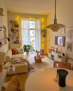 a living room filled with furniture next to a window covered in yellow curtains and lights