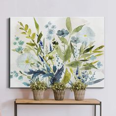 three potted plants sit on a shelf in front of a wall with a painting