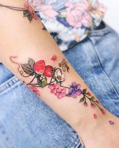 a woman's arm with flowers and hearts tattooed on the left side of her arm