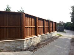 a wooden fence next to a brick wall and concrete block retaining wall with wood slats on the sides