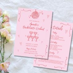 two pink wedding programs on top of a table next to flowers