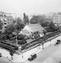 an old black and white photo of a house in the middle of a city street