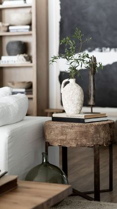 a white vase sitting on top of a wooden table next to a book shelf filled with books