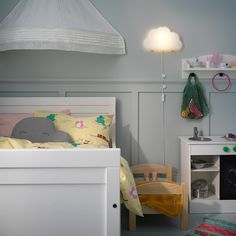 a child's room with a bed, dresser and lamp