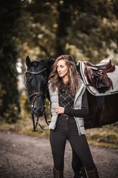 a woman is walking with her horse in the woods