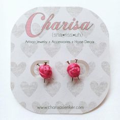 pair of pink flower stud earrings on white card with heart pattern background and name charisha