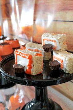 several pieces of cake sitting on top of a black plate with orange and white icing