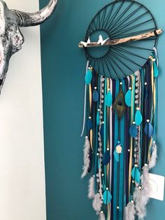 a wall hanging made out of feathers and beads with an animal's head in the background