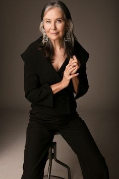 a woman sitting on top of a stool posing for the camera with her arms crossed