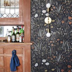 a bar with bottles on the counter and wallpaper in the back ground, next to an open cabinet