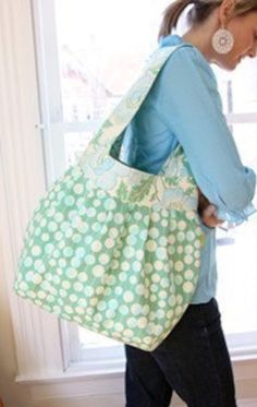 a woman carrying a large green and white polka dot bag in front of a window