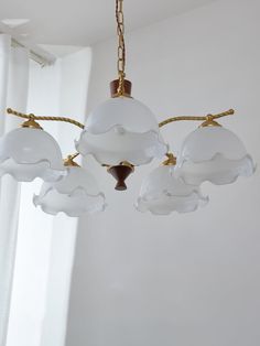 a chandelier hanging from a ceiling in a room with white walls and curtains