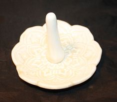 a white ceramic object with a candle holder on it's side, sitting on a black surface