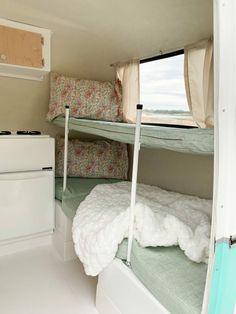 two bunk beds in a small room next to a dresser and window with pillows on it